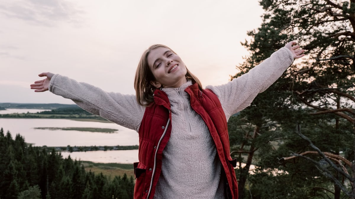 Woman enjoying freedom in a scenic landscape with open arms.